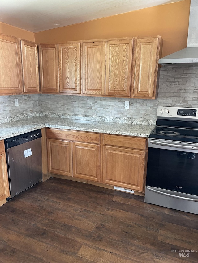 825 S 12th E, Mountain Home, ID 83647 - kitchen featuring stainless steel appliances, wall chimney range hood, tasteful backsplash, dark wood-type flooring, and light stone counters