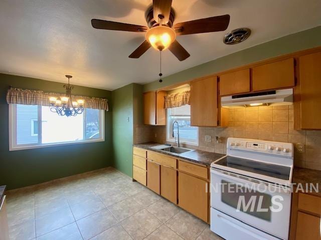 kitchen with dark countertops, under cabinet range hood, electric range, and a sink