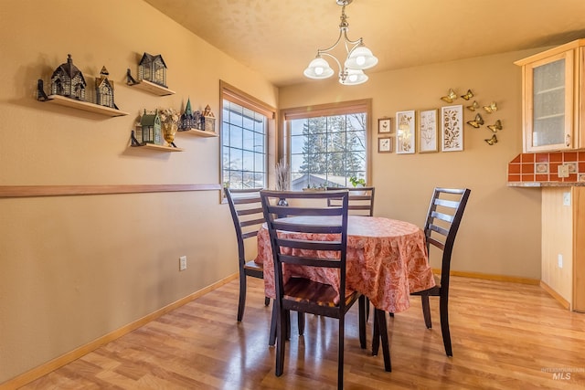 dining area featuring baseboards, light wood-style floors, and a notable chandelier