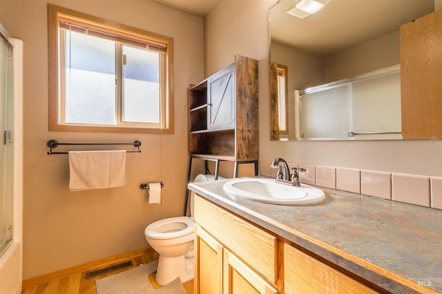 bathroom with visible vents, toilet, a shower with shower door, vanity, and baseboards