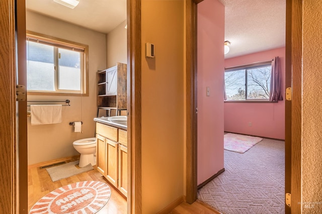 bathroom featuring toilet, baseboards, visible vents, and vanity