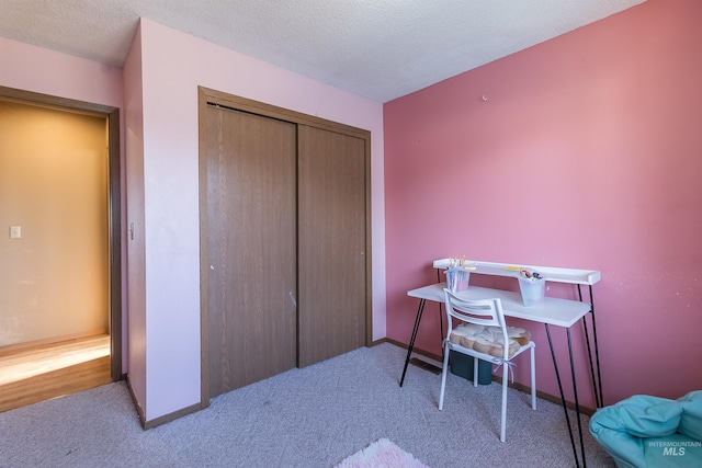 carpeted office space featuring a textured ceiling and baseboards