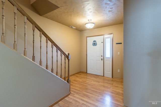 foyer with stairs, baseboards, visible vents, and light wood-style floors