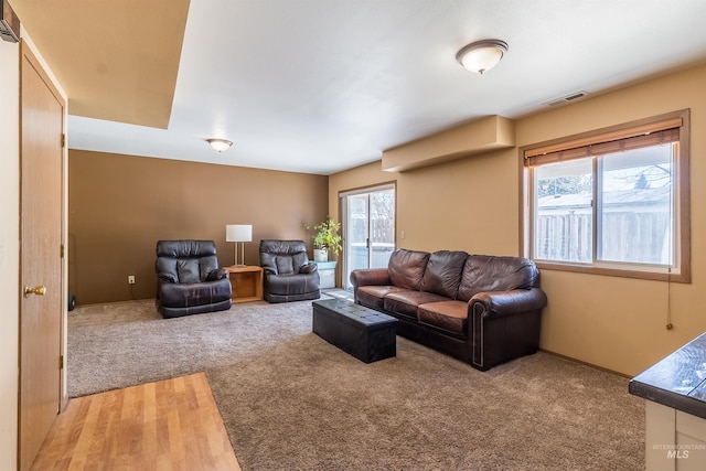 living room featuring light colored carpet, visible vents, and baseboards