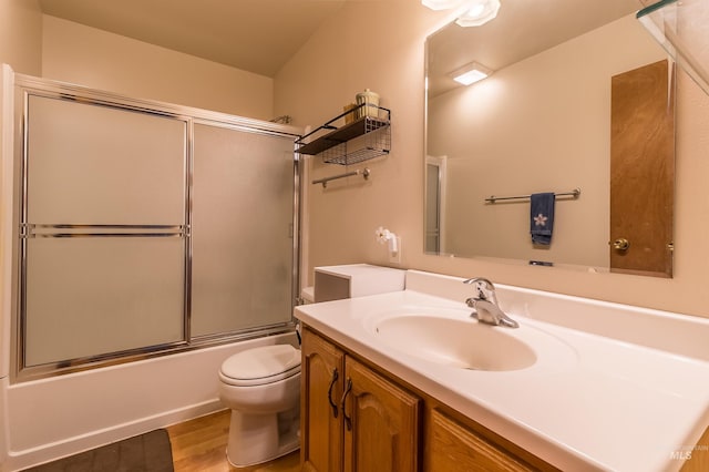 bathroom with toilet, enclosed tub / shower combo, wood finished floors, and vanity