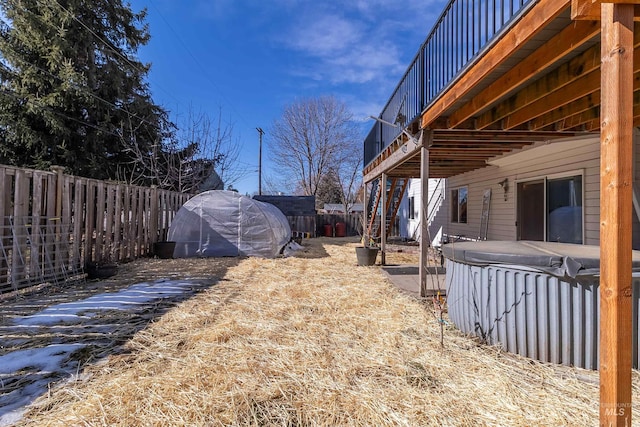 view of yard with a fenced backyard, a hot tub, and a balcony