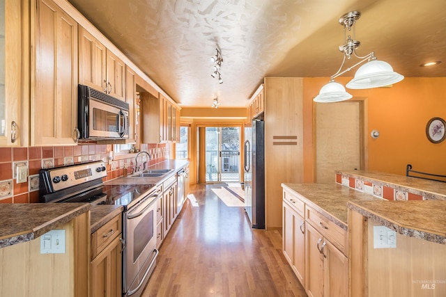 kitchen featuring light wood finished floors, backsplash, appliances with stainless steel finishes, light brown cabinets, and a sink