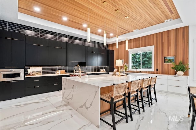 kitchen featuring a large island, stainless steel oven, wooden ceiling, wood walls, and pendant lighting