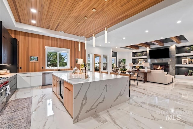 kitchen with light stone counters, wood walls, a spacious island, wood ceiling, and white cabinets