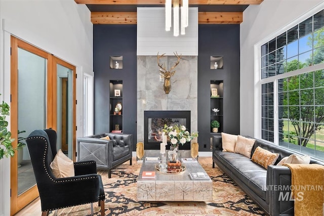 living room with a towering ceiling, a tile fireplace, wood ceiling, and beam ceiling