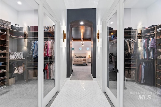 walk in closet with french doors and carpet flooring