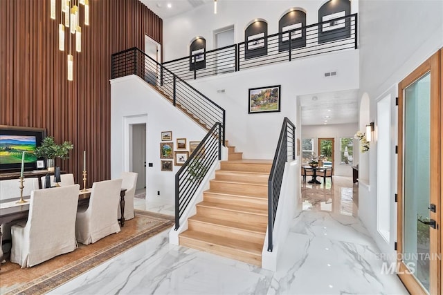 stairway with a towering ceiling and a chandelier