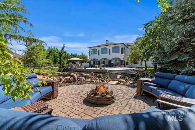 view of patio with an outdoor living space with a fire pit