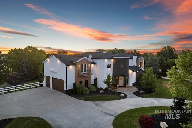 contemporary home with a balcony, a garage, and a yard