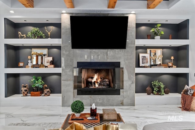 living room with a tile fireplace and built in features