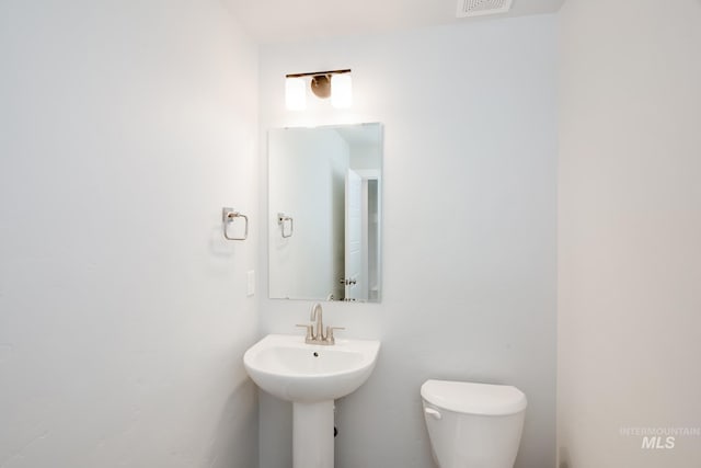 bathroom with a sink, toilet, and visible vents