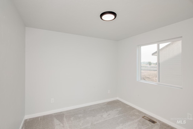carpeted empty room featuring baseboards and visible vents