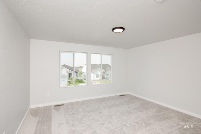 unfurnished room featuring carpet, baseboards, and visible vents