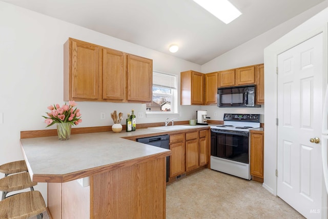 kitchen featuring light countertops, a sink, black appliances, a peninsula, and a kitchen bar