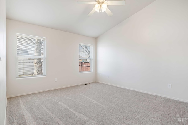 unfurnished room with lofted ceiling, light colored carpet, visible vents, baseboards, and a ceiling fan