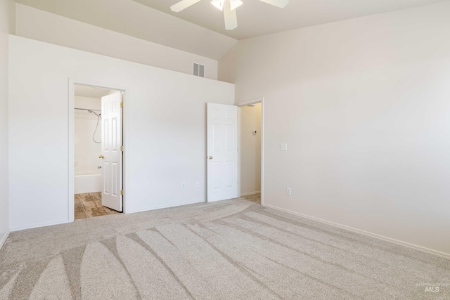 unfurnished bedroom with lofted ceiling, light colored carpet, visible vents, ensuite bathroom, and a ceiling fan