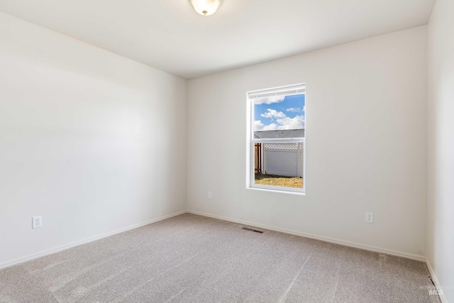 carpeted spare room featuring visible vents and baseboards