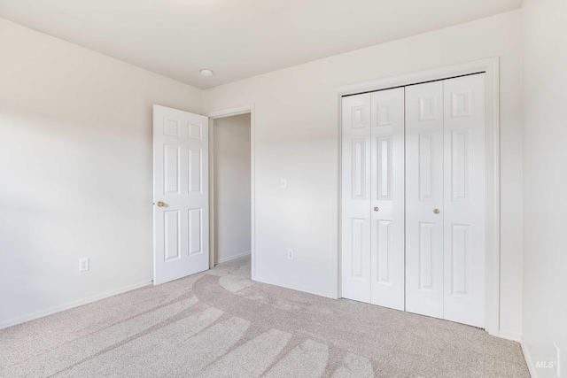 unfurnished bedroom featuring a closet and light colored carpet