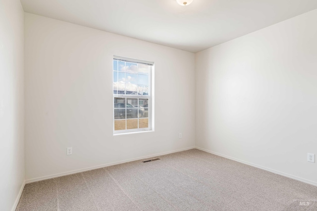 carpeted spare room featuring visible vents and baseboards