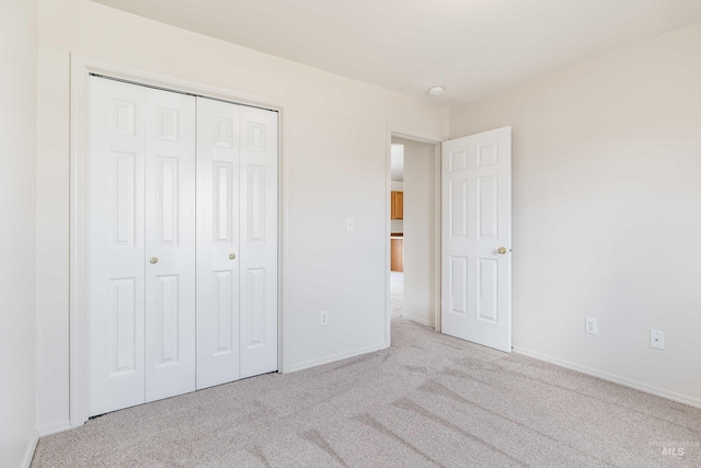 unfurnished bedroom featuring a closet, light carpet, and baseboards