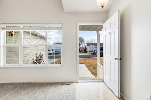 doorway to outside with carpet, visible vents, and baseboards