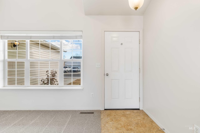 doorway to outside with light colored carpet, visible vents, and baseboards