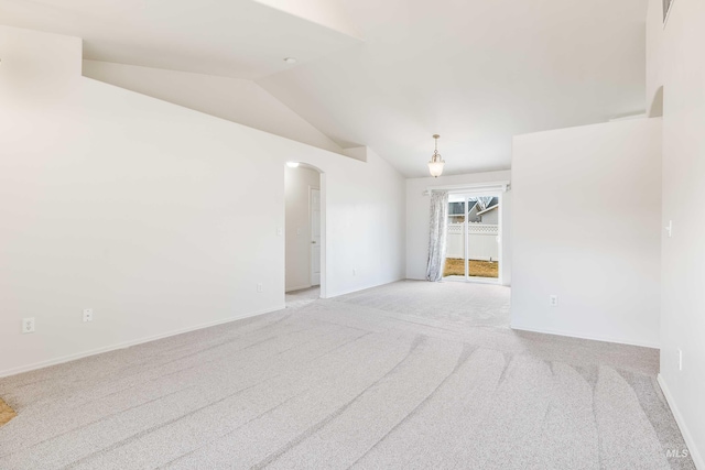 empty room with lofted ceiling, baseboards, light carpet, and arched walkways