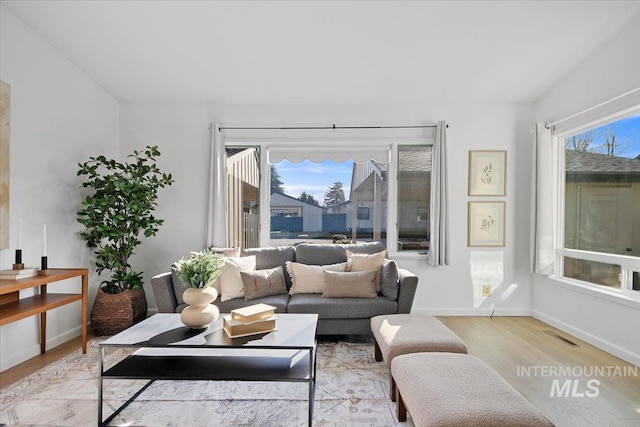 living room with visible vents, a healthy amount of sunlight, light wood-style floors, and baseboards