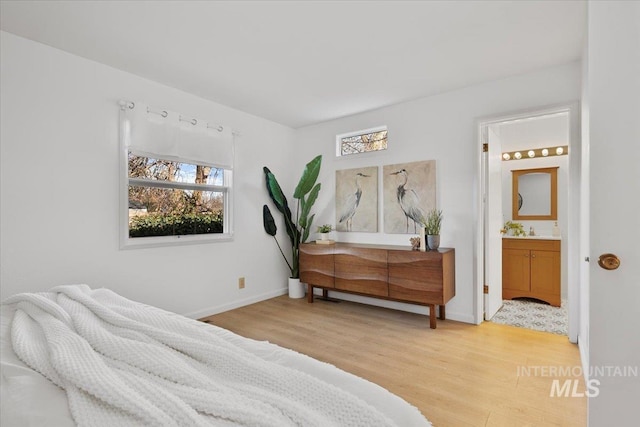 bedroom featuring multiple windows, baseboards, and light wood-type flooring