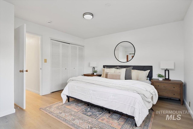 bedroom with a closet, baseboards, and light wood-style floors