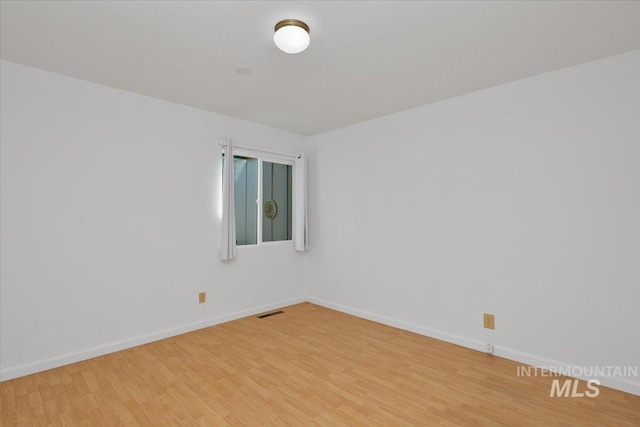 empty room with visible vents, light wood-style flooring, and baseboards