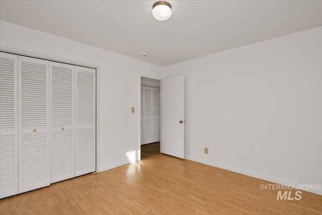 unfurnished bedroom featuring a closet, baseboards, and light wood-style floors