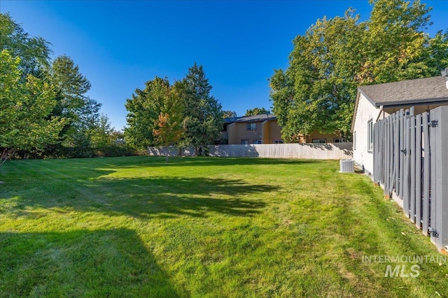 view of yard featuring central AC unit and fence