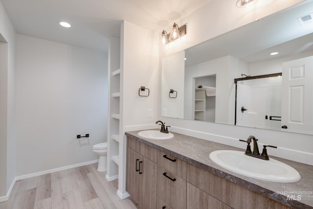 1516 N Coltsfoot Ave, Kuna, ID 83634 - full bathroom with double vanity, a shower stall, wood finished floors, toilet, and a walk in closet
