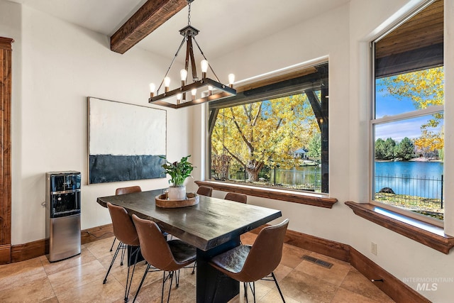 tiled dining area featuring an inviting chandelier, beam ceiling, and a water view