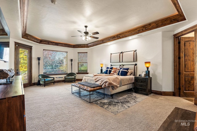 carpeted bedroom with ceiling fan, a raised ceiling, a textured ceiling, and crown molding