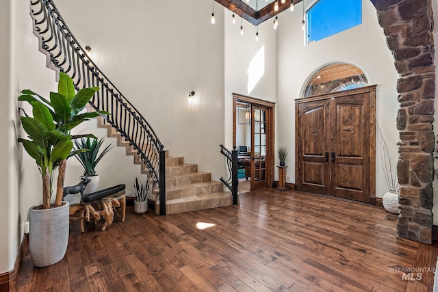 entryway featuring dark wood-type flooring and a towering ceiling