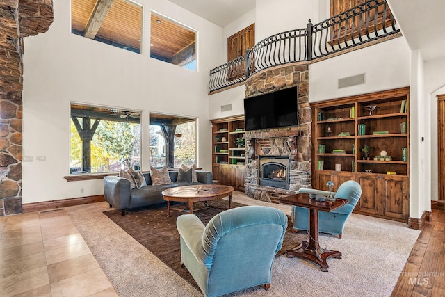 living room with a towering ceiling, hardwood / wood-style floors, wooden ceiling, and a fireplace