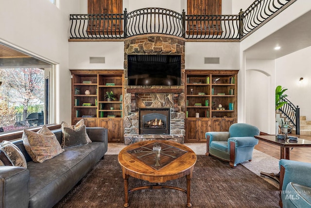 living room with a high ceiling, a wealth of natural light, a fireplace, and hardwood / wood-style floors