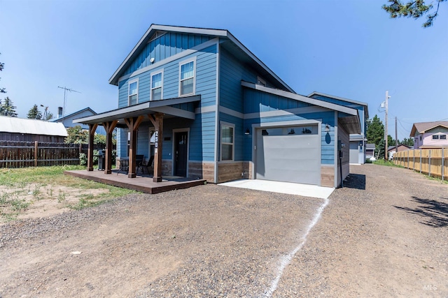 view of front facade featuring covered porch, board and batten siding, fence, a garage, and driveway