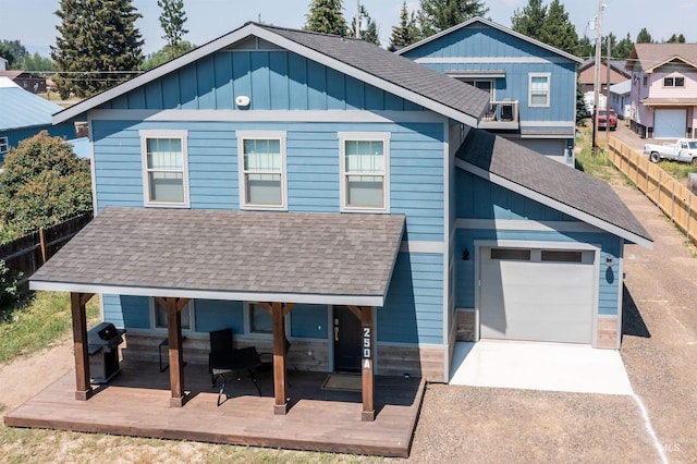 view of front of house with a shingled roof, board and batten siding, fence, a garage, and driveway