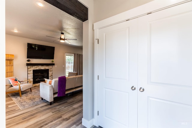 living room with a ceiling fan, recessed lighting, a stone fireplace, and wood finished floors