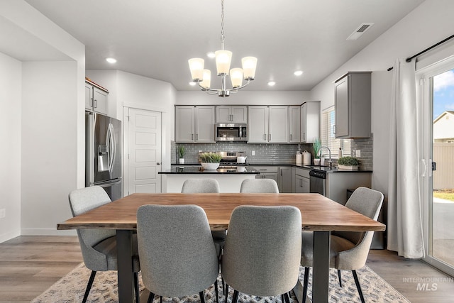 dining area featuring sink, light hardwood / wood-style flooring, and an inviting chandelier