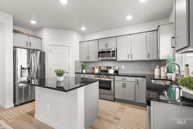 kitchen featuring light hardwood / wood-style flooring, stainless steel appliances, a kitchen island, gray cabinets, and sink