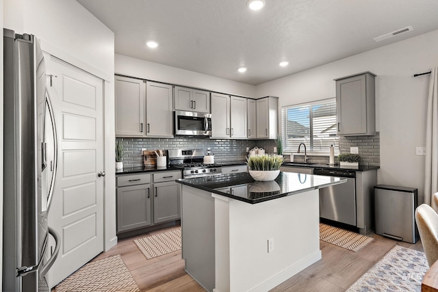 kitchen featuring a center island, light wood-type flooring, gray cabinetry, and appliances with stainless steel finishes